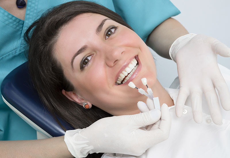 Bei einer Frau auf einem Zahnarztstuhl wird die Zahnfarbe bestimmt.