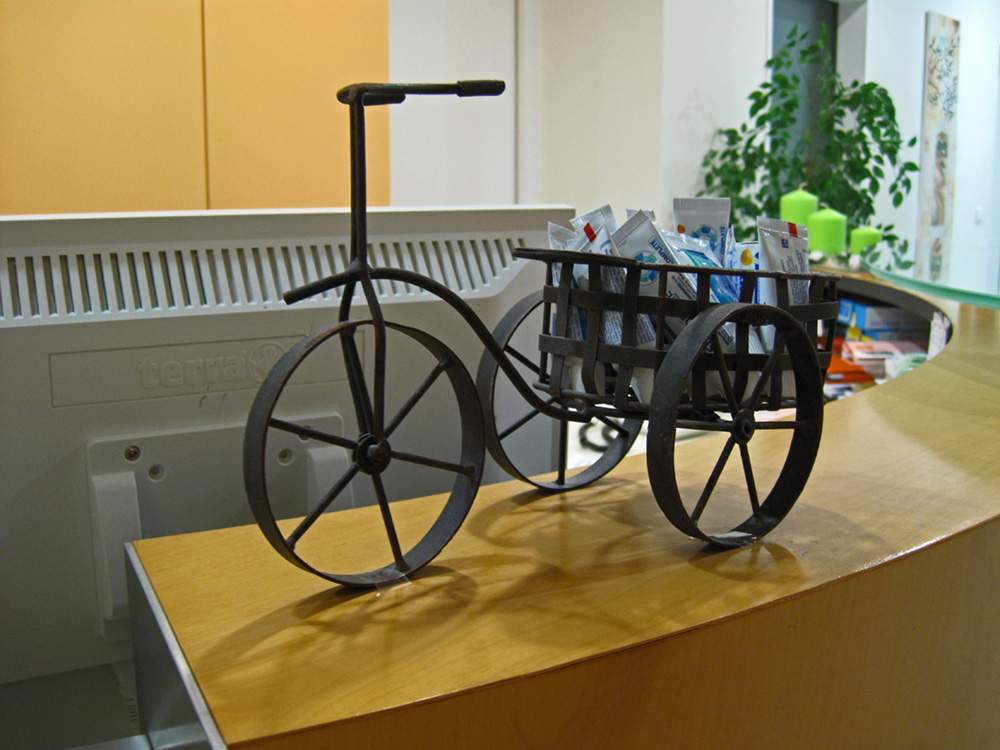 Detailfoto eines Dekofahrrads aus Metall auf der Holztheke.